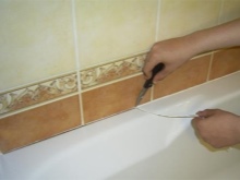 Премахване на старата фугираща смес от фугата между ваната и стената.