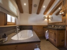 Träbjälkar, taklampor och vitkalkade väggar i ett badrum i chaletstil