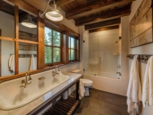 Trätak, en enda metallarmatur, vitkalkade väggar, stengolv - det här är ett badrum i chaletstil.