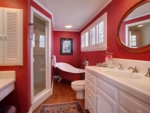 Punainen sisustus kylpyhuoneeseen, jossa on valkoiset kalusteet ja saniteettitarvikkeet.