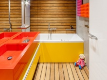 Keltainen kylpyamme, oranssit pesualtaat kylpyhuoneen sisustuksessa yhdistettynä wc:hen