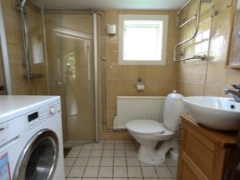 Kylpyhuoneen sisätilat yhdistettynä wc:hen, jossa on suihkukaappi, pesukone, allaskaappi ja WC