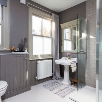 Keraamiset laatat, lastulevy ja harmaa rappaus kylpyhuoneen sisätiloihin yhdistettynä wc:hen.