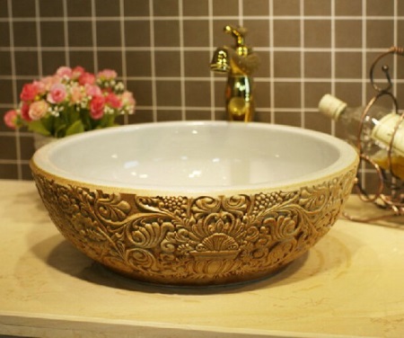 Ronde wastafel met goudmotieven op de buitenkant van de kom, 55cm breed.