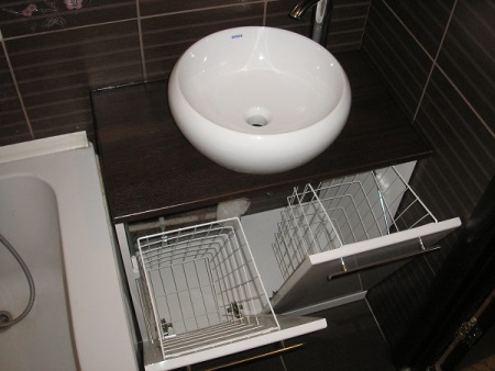 Overhead basin cabinet with integrated laundry basket