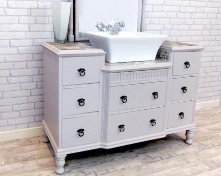 Ett vitt golvskåp med många lådor och ett toppmonterat handfat i badrummet. 